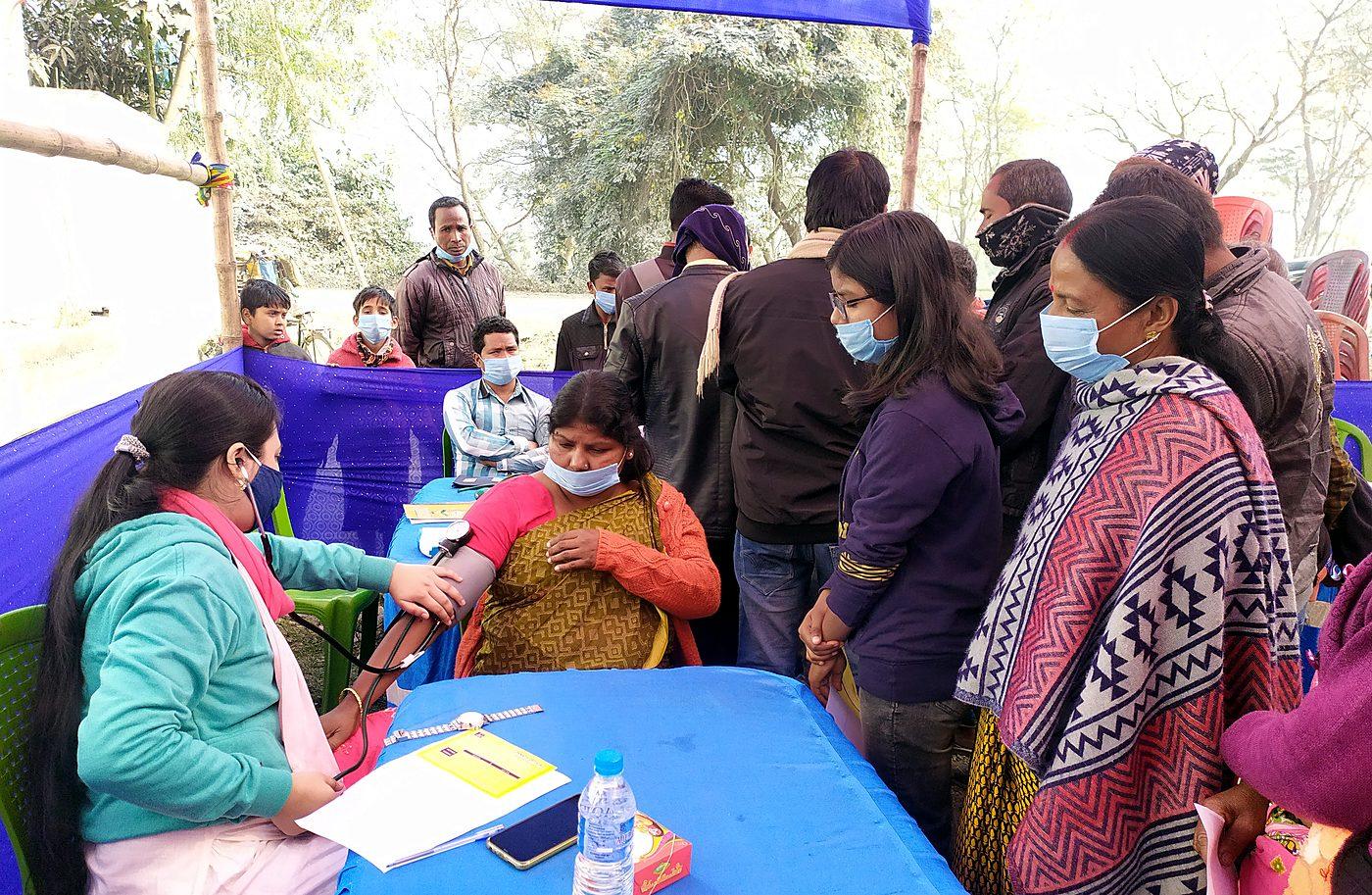 Nurse taking a patient's blood pressure at a community health camp